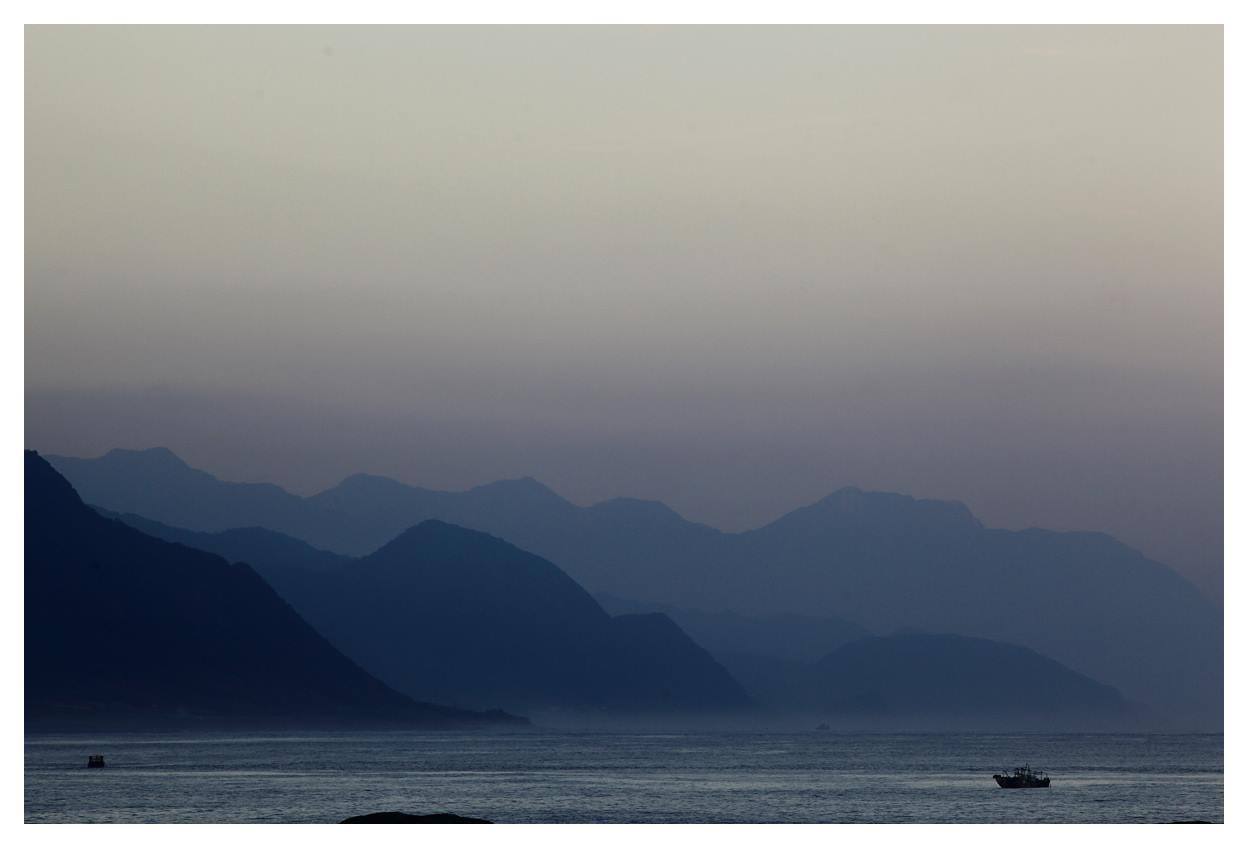 花蓮山巒風景，暮色中層疊的山稜線與海面漁船